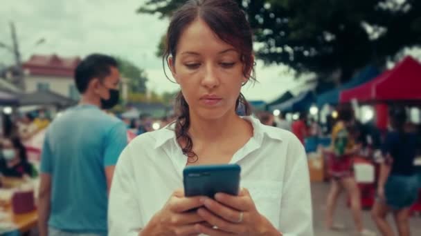 Porträt einer jungen Frau, die auf der Straße auf einem Smartphone tippt — Stockvideo