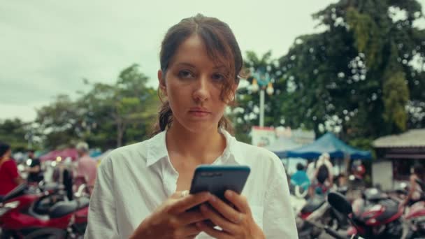 Sokakta akıllı bir telefonla yazı yazan genç bir kadının portresi. — Stok video