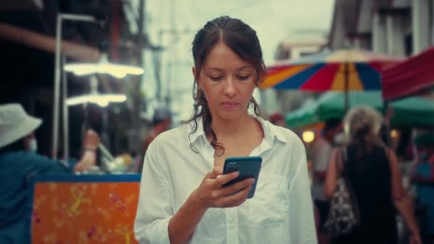 Sokakta akıllı bir telefonla yazı yazan genç bir kadının portresi. — Stok video
