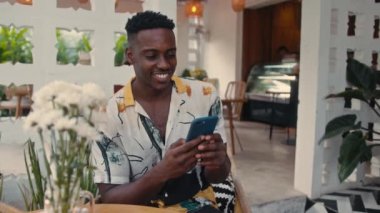 Genç Afro-Amerikalı adam açık havada akıllı telefon kullanıyor.