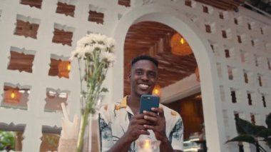 Genç Afro-Amerikalı adam açık havada akıllı telefon kullanıyor.