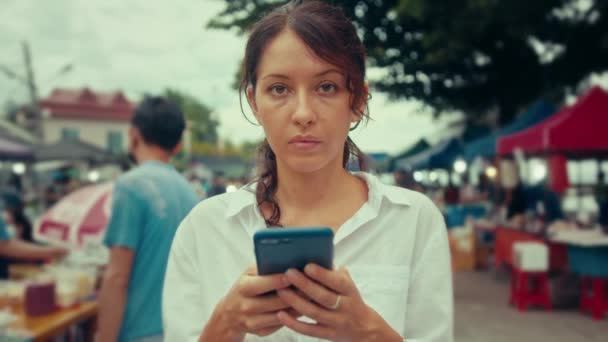 Egy fiatal nő portréja, amint egy okostelefonon gépel az utcán. — Stock videók