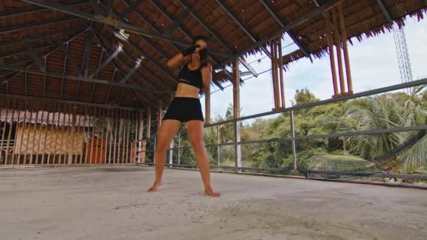 Mujer luchadora entrena sus golpes, día de entrenamiento en el hotel abandonado, cuerpo en forma de fuerza — Vídeo de stock