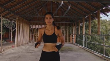 Kadın dövüşçü yumruklarını eğitiyor, terk edilmiş otelde antrenman günü, güçlü bir vücut.