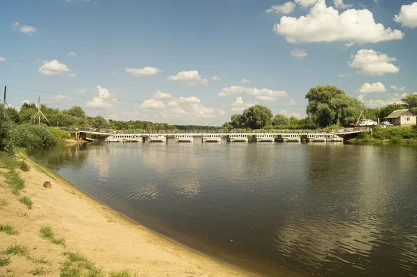 Říční krajina s mostem na pozadí modré oblohy — Stock fotografie