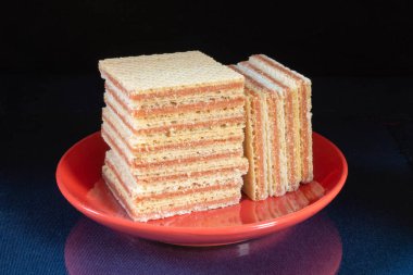 Lezzetli gofret kırmızı tabakta masanın üzerinde duruyor. Siyah arkaplanda beslenmenin tatlı ürünleri