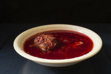 Masasında beyaz tabakta et olan Red Borsch. Beslenmenin siyah arka plandaki ürünleri