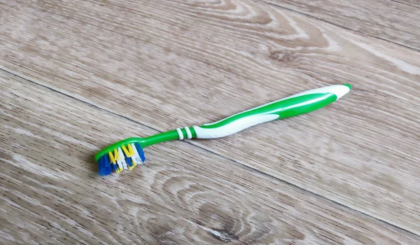  Diş fırçası ahşap masaya dayanıyor. Ağız boşluğunun soyulması için gerekli alet.
