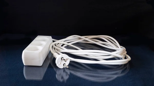 Ağ uzantısı kablosu yansıması olan cam masanın üzerinde duruyor. Siyah arkaplan üzerine konular