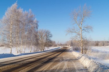 Arka plandaki huş ağacı ile mavi gökyüzü arasındaki kış yolu. Rusya 'nın güzel manzarası