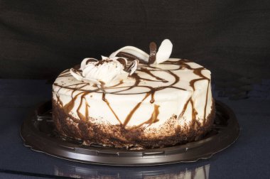 Tatlı bir pasta cam bir masanın üzerinde yansımalı duruyor. Siyah arkaplanda yemek