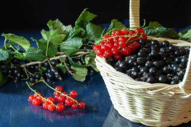 Masadaki sepetteki kırmızı frenk üzümü. Gıda ürünleri siyah arka planda