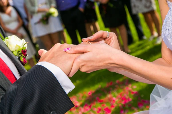 Bride putting a wedding ring on groom's finger — Stock Photo, Image