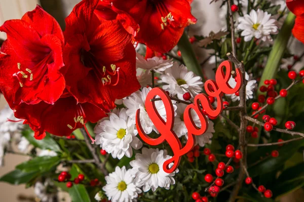 Flores vermelhas com sinal de madeira Amor — Fotografia de Stock