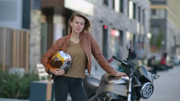 Портрет Приваблива байкерка стоїть на мотоциклі з шоломом у місті — стокове відео