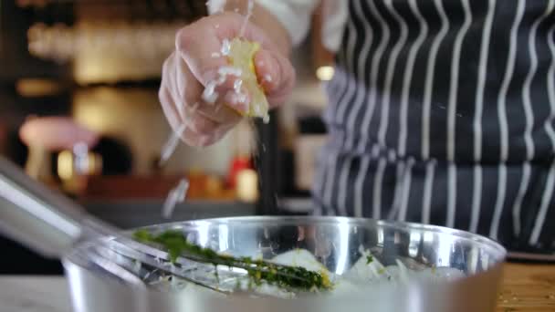 Großaufnahme: Küchenchef drückt in Restaurantküche eine halbe geschnittene Zitrone aus dem Salat — Stockvideo