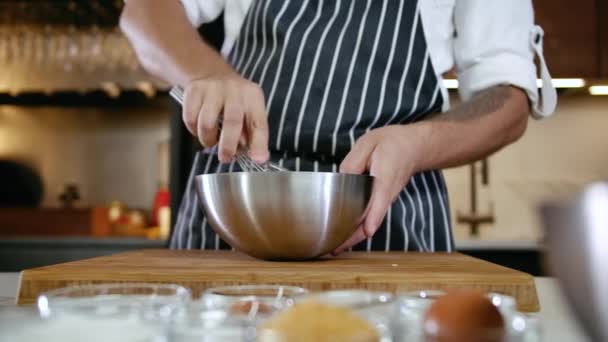 Close-up Mann Hand Chef Mischen Lebensmittel Zutat in Stahlschüssel Schneebesen in der Küche 4k — Stockvideo