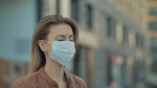 Портрет крупным планом Молодая женщина носит защитную медицинскую маску и смотрит — стоковое видео