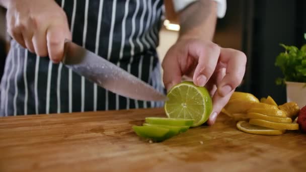 Крупный план Man Chef Cuts Fresh Fruits Lemon and Lime on Wooden Cutting Board — стоковое видео