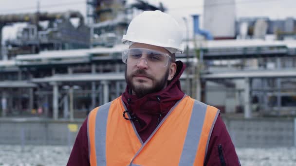 Portret inżyniera w twardej czapce, gogle, mundur bezpieczeństwa w tle przemysłowym — Wideo stockowe