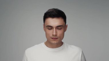 Color Studio Shot 'da kameraya bakan genç adamın portresi. Yetişkin Çocuk Gri Arka plan 'da tek başına yakın plan çekimde izole edildi. Güzel yirmili yaşlarda moda tişörtlü yükselen kafa ve parlak güzel gözler.