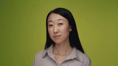 Renkli Stüdyo Çekimde Kameraya Bakan Genç Koreli Kadın Portresi. Yetişkin Japon Kız, Kahverengi Arka planda Tek Başına Yakından İzole Edildi. Mutlu Arkadaş Yüzlü, Gülümseyen ve Açık Gözlü Asyalı