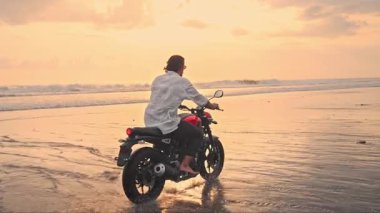 Motosikletli Sürücü ya da Sahilin Güzel Doğasında Seyahat. Moto Bisikletli Yakışıklı Yarışçı Motorlu Kum Kumu ile Hızlı Hareket Ediyor. Motosiklet Gezisinde Yetişkin Özgürlüğü