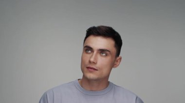 Color Studio Shot 'a bakan genç adamın portresi. Yetişkin Çocuk Gri Arkaplan 'da yalnız başına yakın planda. Dalgın Erkek Bakışları Düşünceli Düşünmeye ya da Kusursuz Fikir 4k 'ye Odaklanmış