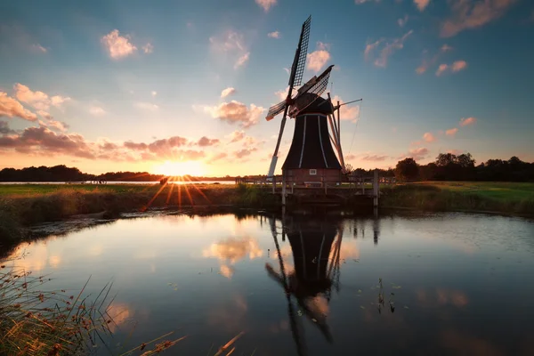 Nederlandse windmill door meer bij zon beneden — Stockfoto