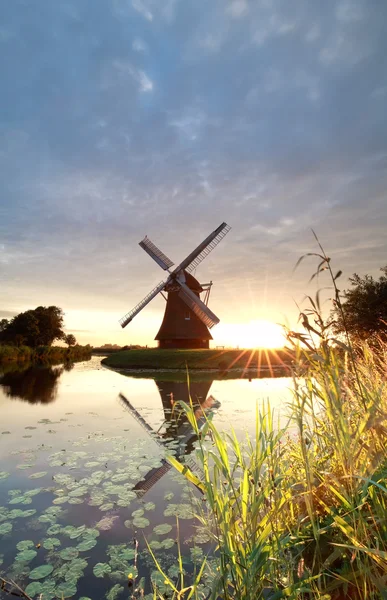 Sol de oro detrás del molino de viento holandés por río —  Fotos de Stock