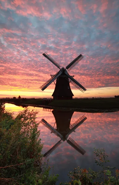 Molino de viento y cielo dramático amanecer reflejado en el río — Foto de Stock