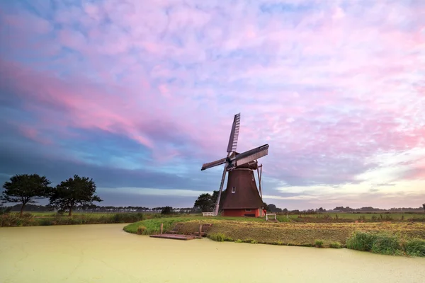 Oude windmill door meer bij zonsopgang — Stockfoto