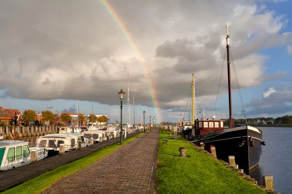 Regnbue over Zoutkamp havn med båt – stockfoto