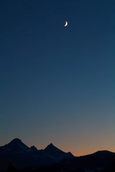 Månen och mountain silhuetter över mörk himmel — Stockfoto