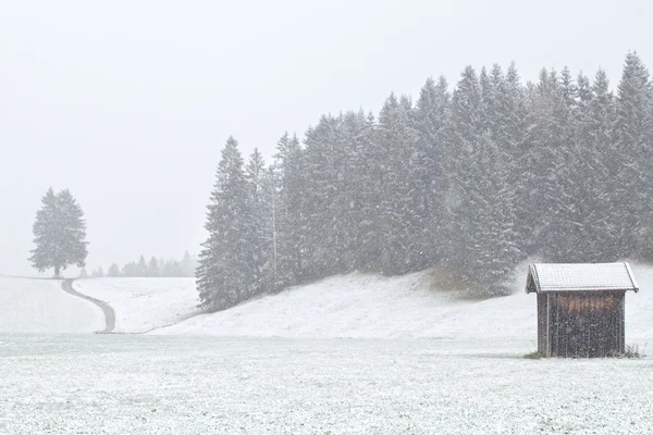 Staré chatě a kopce v sněhová bouře — Stock fotografie