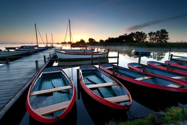 Red boats on harbor at sunrise — Stock Photo, Image