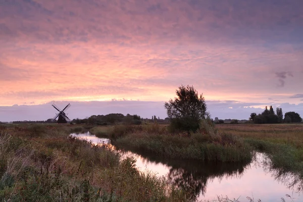 Moinho de vento holandês por rio ao nascer do sol — Fotografia de Stock
