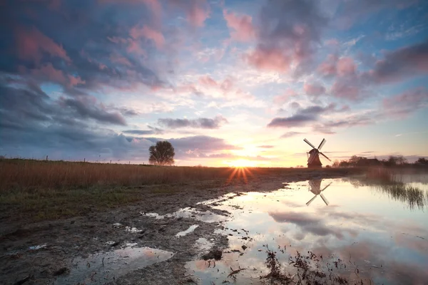 Holländsk väderkvarn vid soluppgången vid floden — Stockfoto