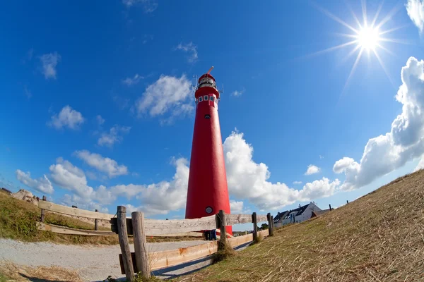 Sluníčko a červený maják věž na pobřeží — Stock fotografie