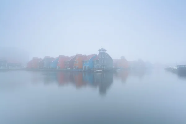 Colorful buildings on water in foggy morning — Stock Photo, Image