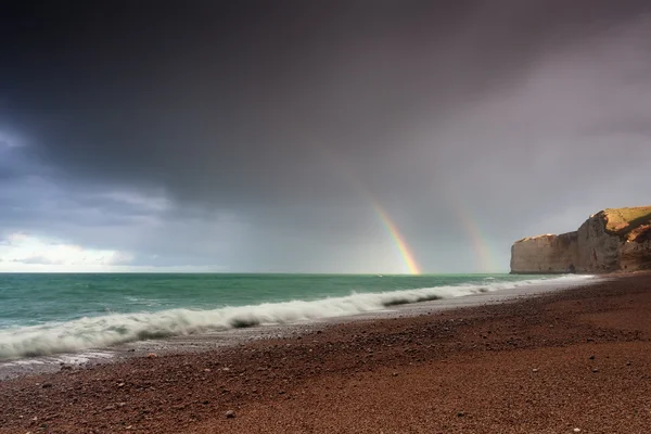 Rainbow over sea waves by rock after shower — Stock Photo, Image