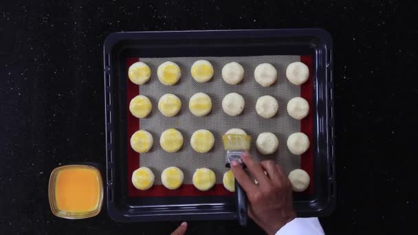 Chef grasse la pâte à biscuits avec des jaunes d'oeuf à l'aide d'une brosse — Video