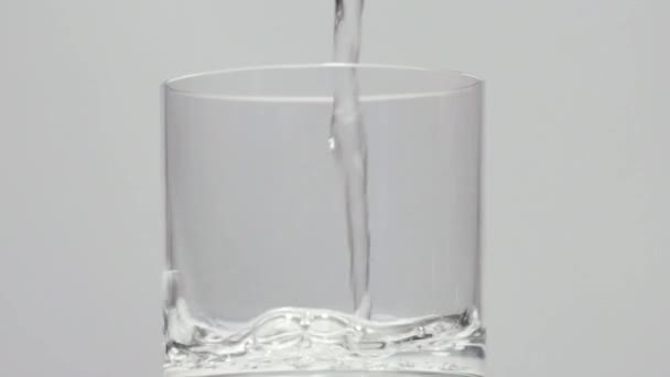 Наливаємо воду в склянку з льодом на білому фоні — стокове відео