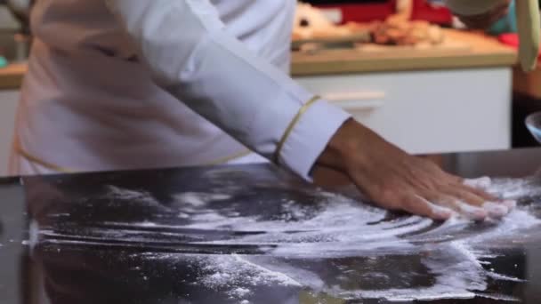 Um chef experiente em uma cozinha profissional prepara a massa, com farinha. — Vídeo de Stock