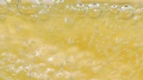 Makro-Nahaufnahme von kaltem, erfrischendem Soda Tonic sprudelndem Wassergetränk mit Blasen, die mit Eis und Kalk interagieren — Stockvideo