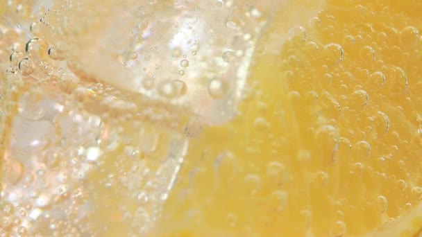 Macro close-up shot of cold refreshing soda tonic fizzy water drink with bubbles interacting with ice and lime — Stock Video