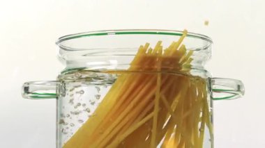 Geleneksel İtalyan mutfağı yavaş çekimde makarna beyaz arka planda suya atılıyor.