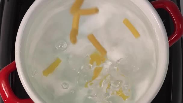 Kamera folgt dem Einwerfen von Penne-Nudeln ins Wasser. Kopfschuss. Zeitlupe. — Stockvideo