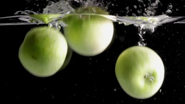 Groene appels vallen op een zwarte achtergrond in het water — Stockvideo