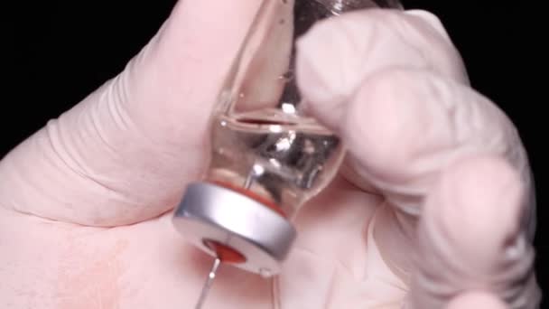De naald van de spuit haalt het geneesmiddel uit een glazen injectieflacon — Stockvideo